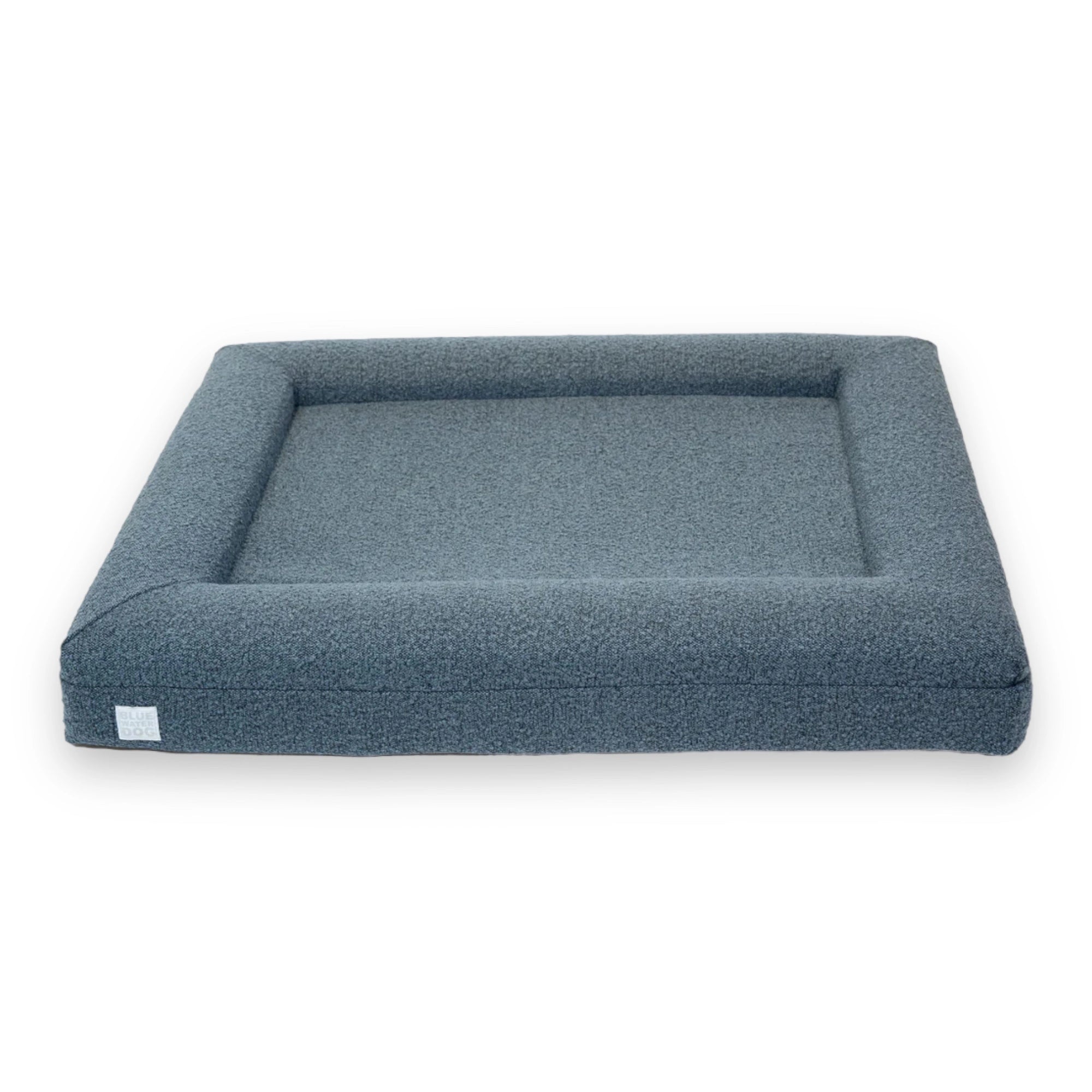 Front of a large, blue-colored orthopedic memory foam rectangular boucle dog bed with bolsters.