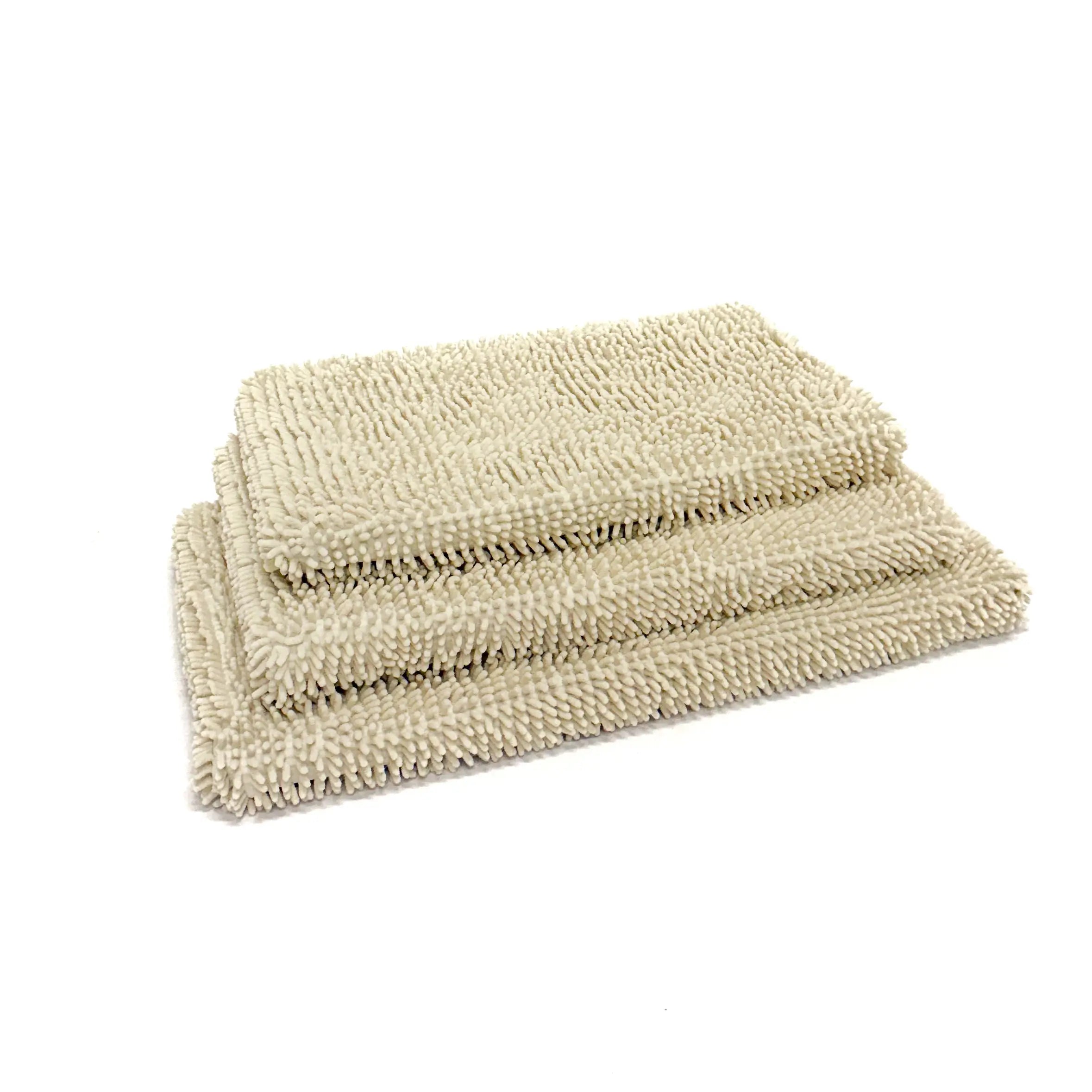 Dog crate pads with towel covers stacked on top of each other on a white background.