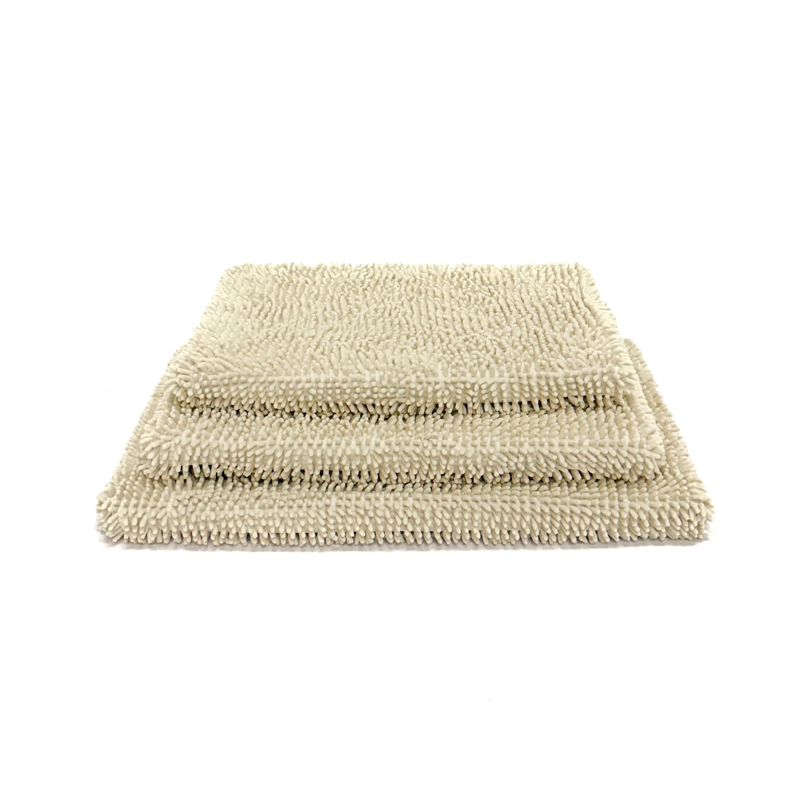 Dog crate pads with towel covers stacked on top of each other on a white background.