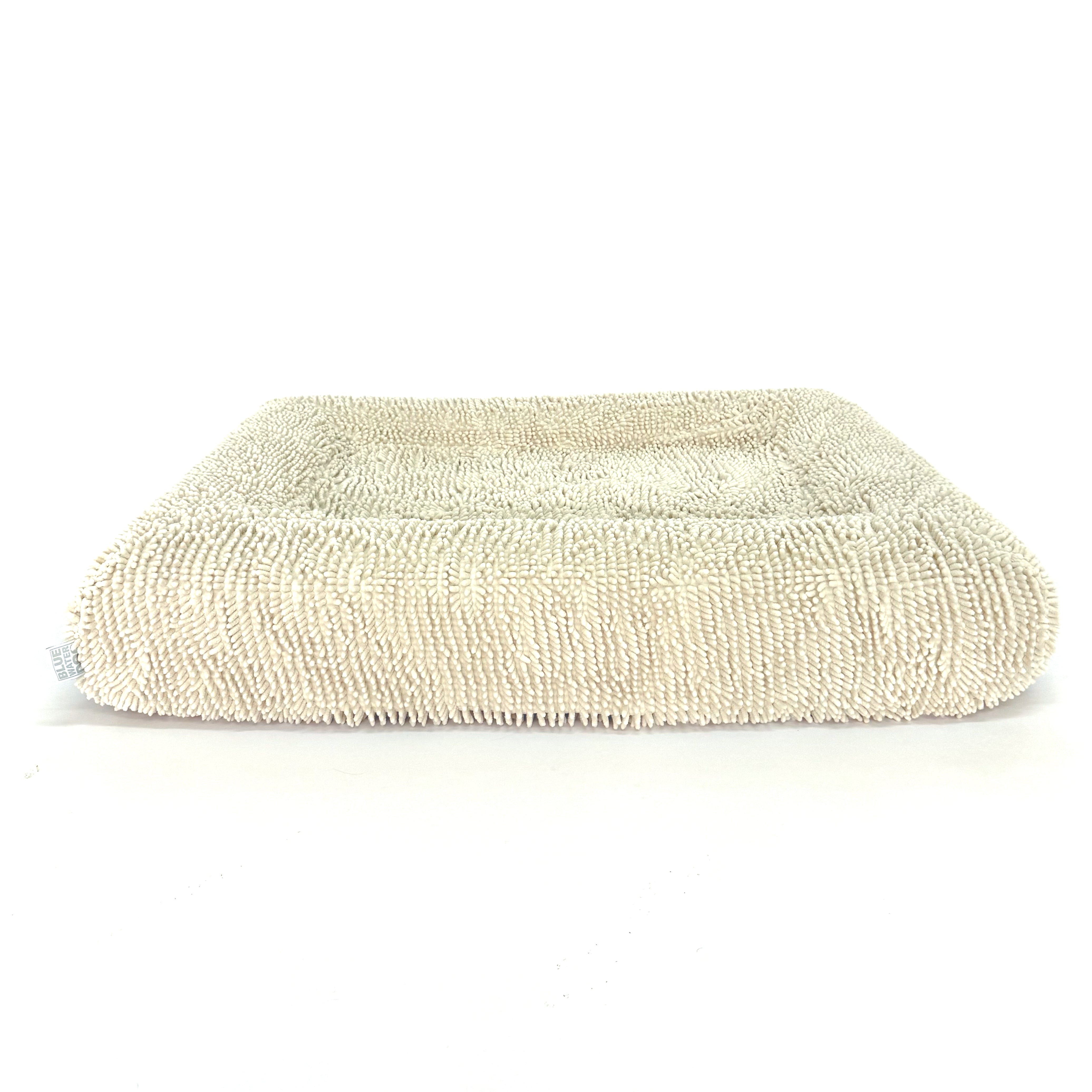 Beige pet bed with towel cover on a white background