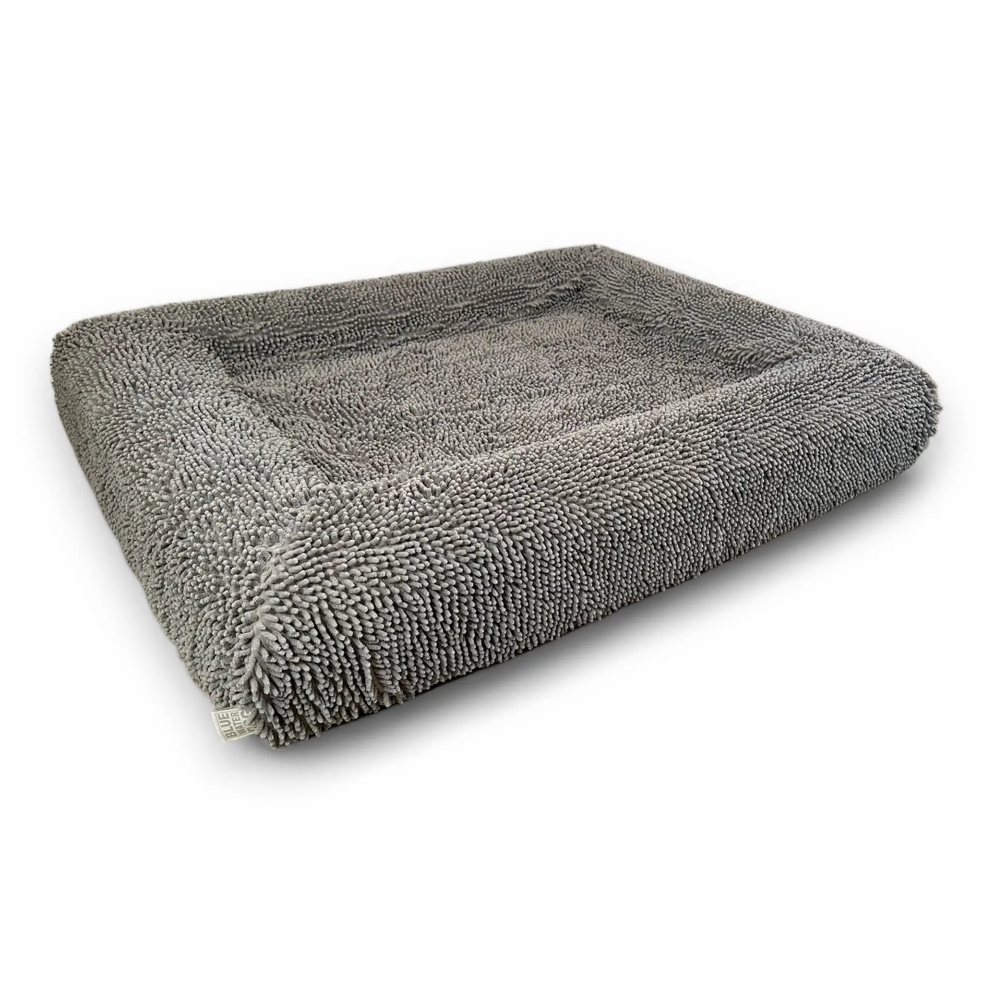 Side of a gray-colored shaggy towel cover on top of an orthopedic memory foam rectangular dog bed with bolsters.