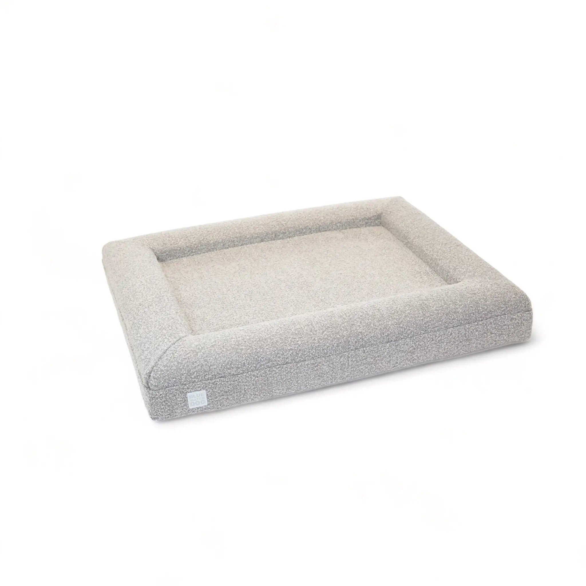 Side of a large, sand-colored orthopedic memory foam boucle dog bed with bolsters.