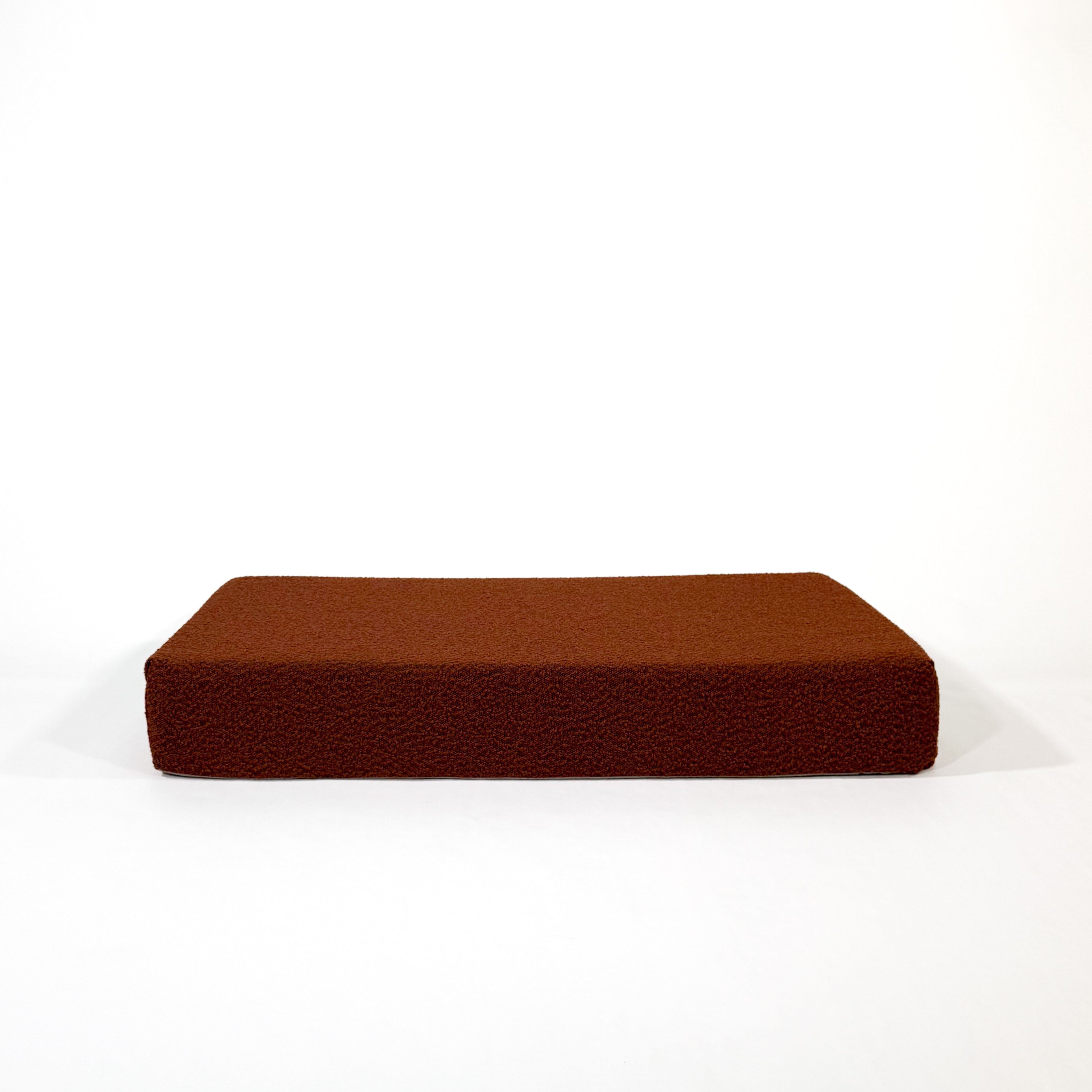 A pumpkin spice colored dog bed against a white background