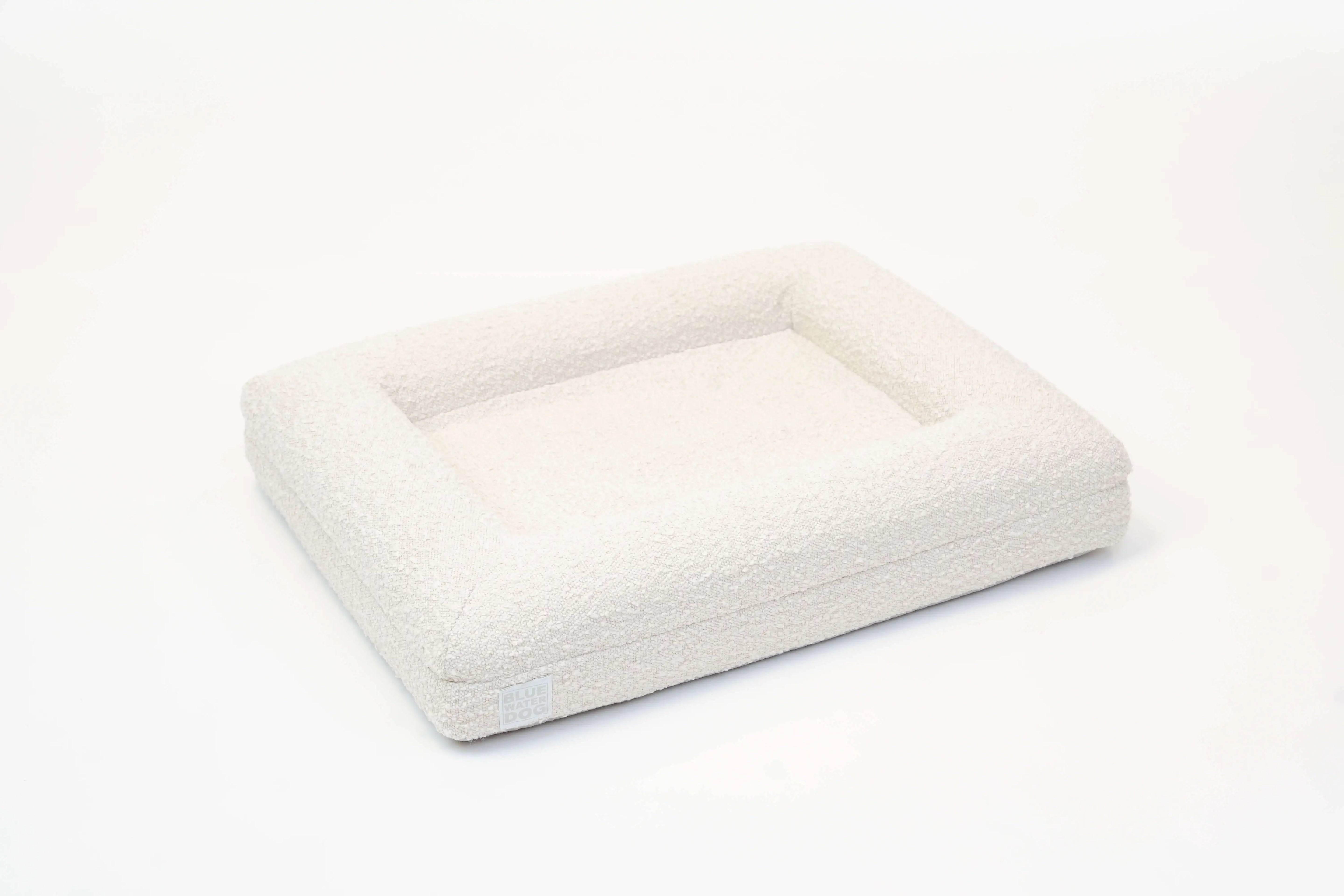 Side of a small, cloud-colored orthopedic memory foam boucle dog bed with bolsters