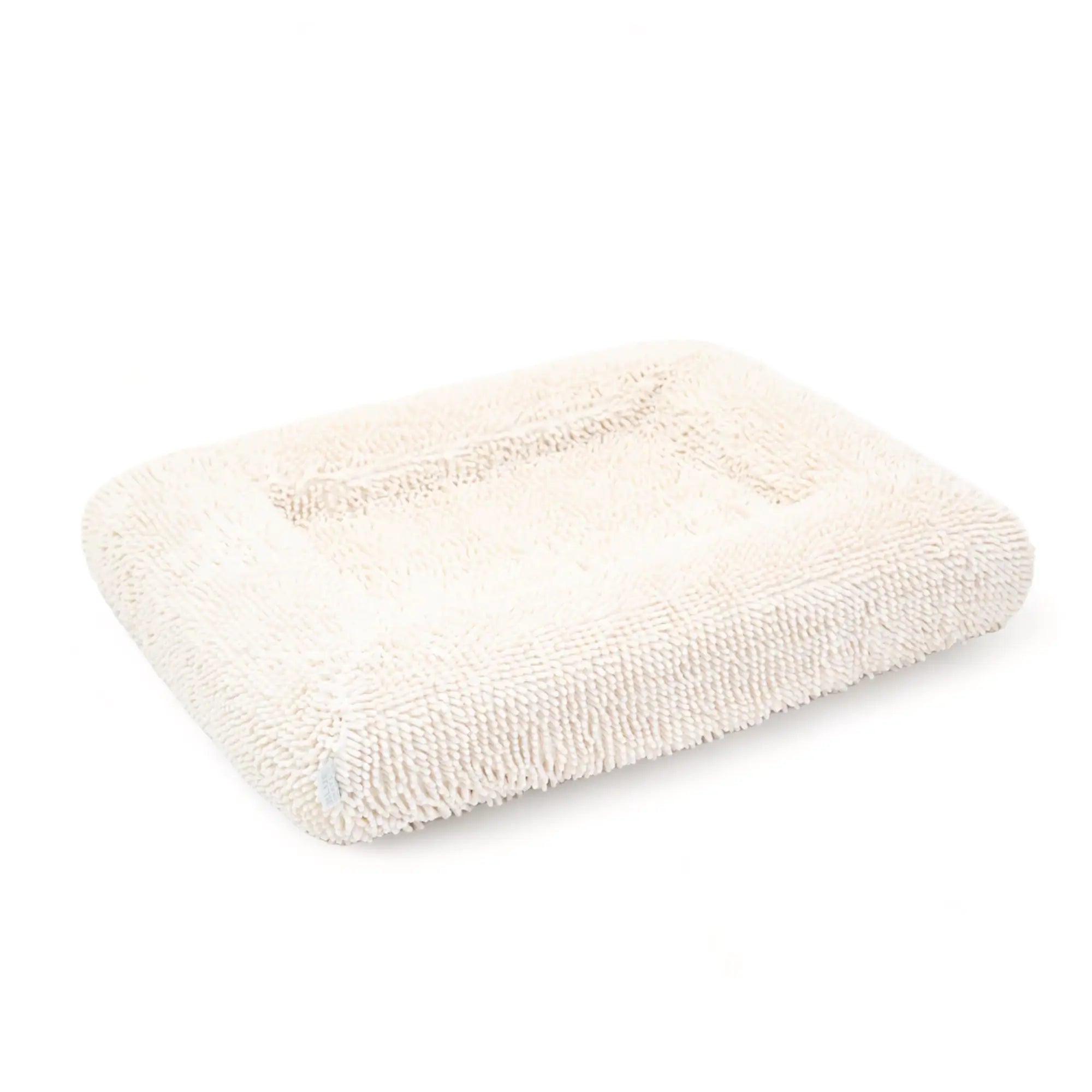 Side of a cream-colored shaggy towel cover on top of an orthopedic memory foam rectangular dog bed with bolsters.