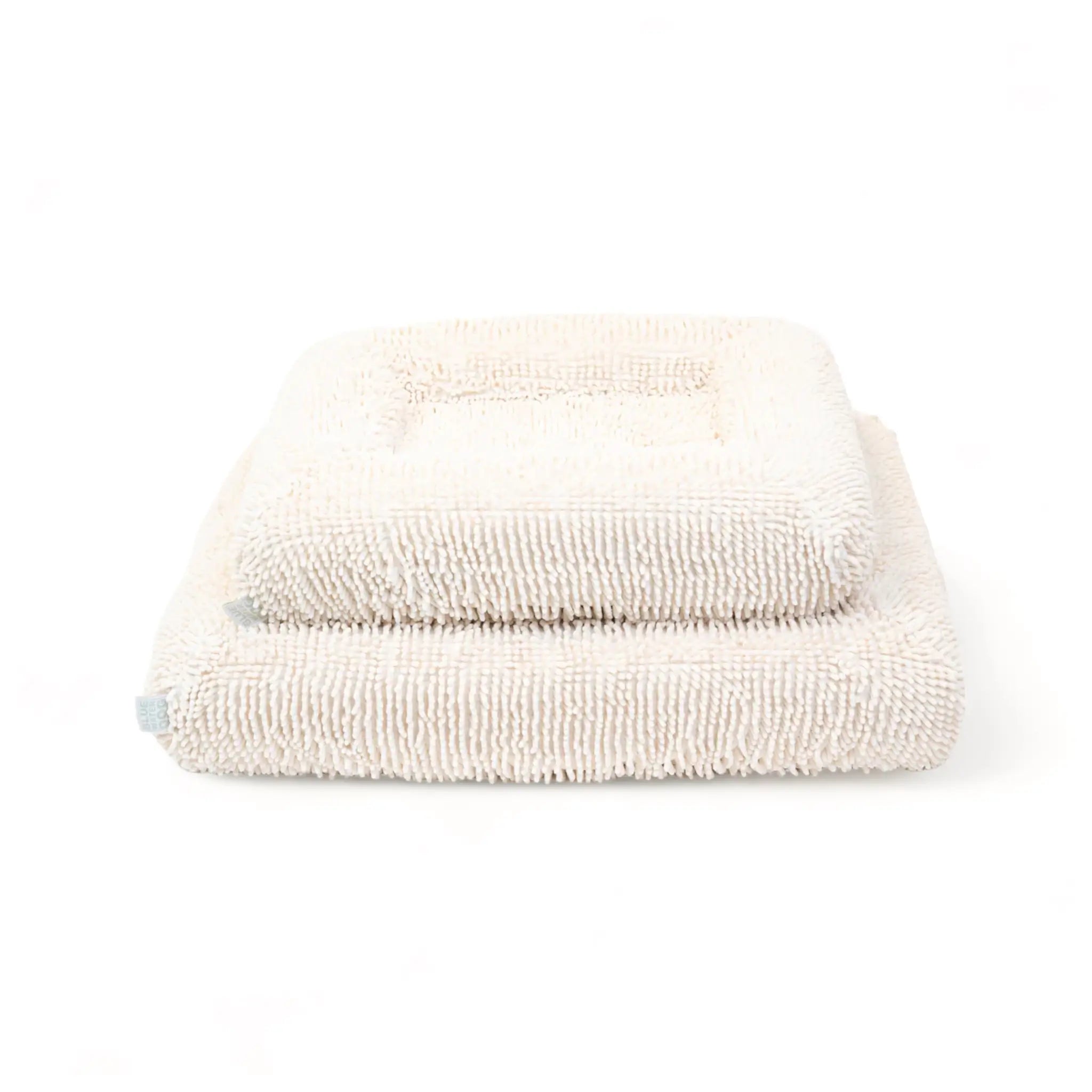 Two orthopedic memory foam dog beds with cream-colored shaggy towel covers stacked on top of each other.