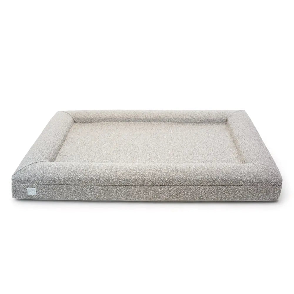 Front of an extra large, sand-colored orthopedic memory foam rectangular boucle dog bed with bolsters.