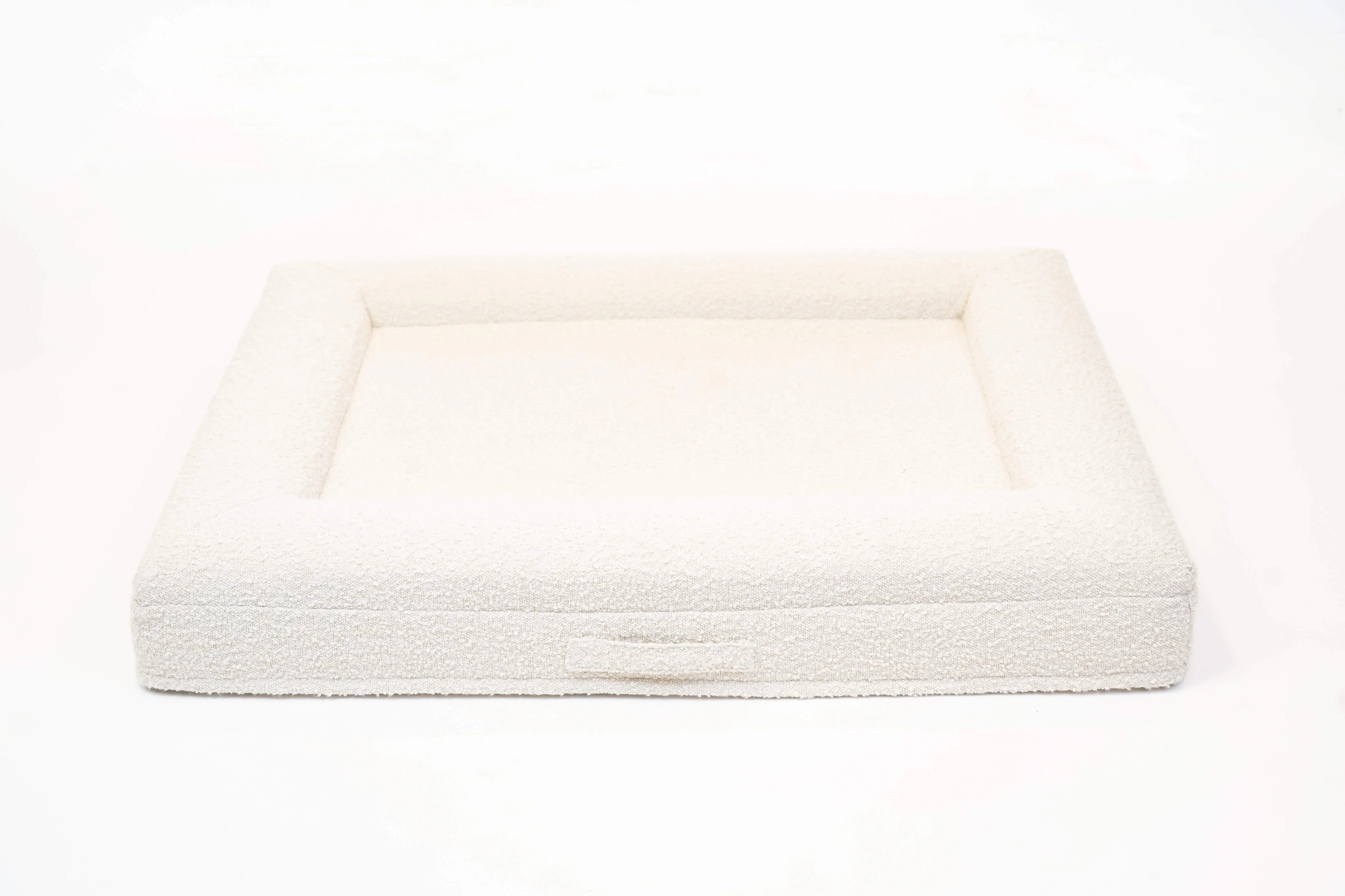 Back of a large, cloud-colored orthopedic memory foam boucle dog bed with bolsters and a handle for easy transport.