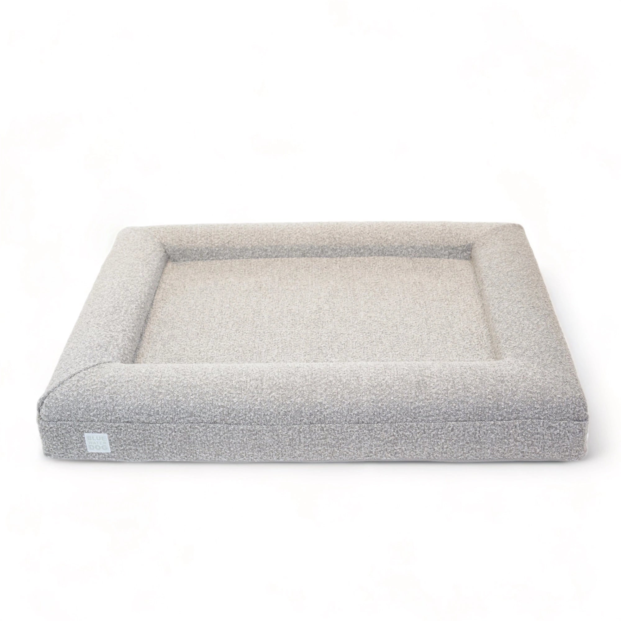 Front of a large, sand-colored orthopedic memory foam rectangular boucle dog bed with bolsters.
