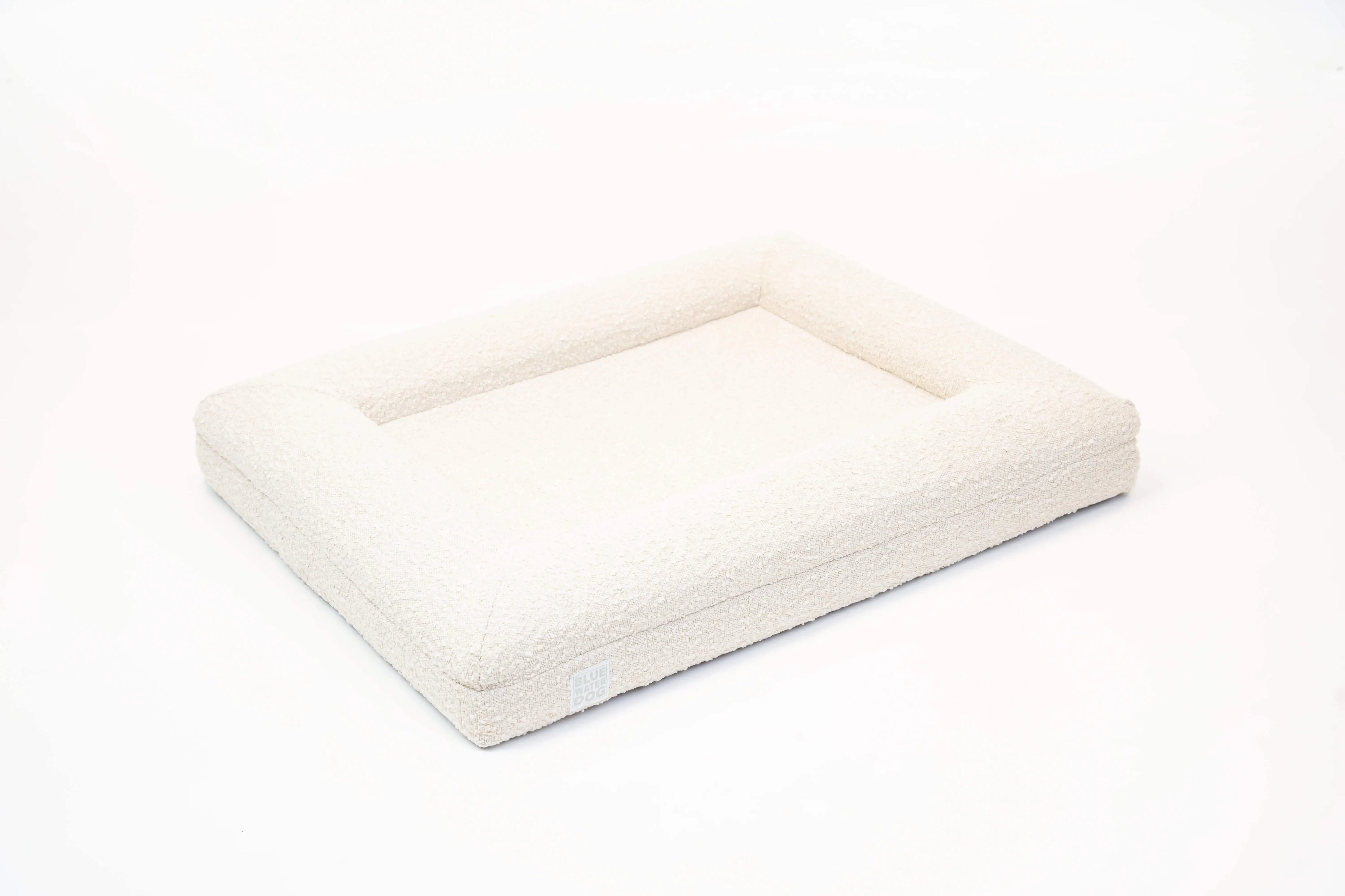 Side of a medium, cloud-colored orthopedic memory foam boucle dog bed with bolsters