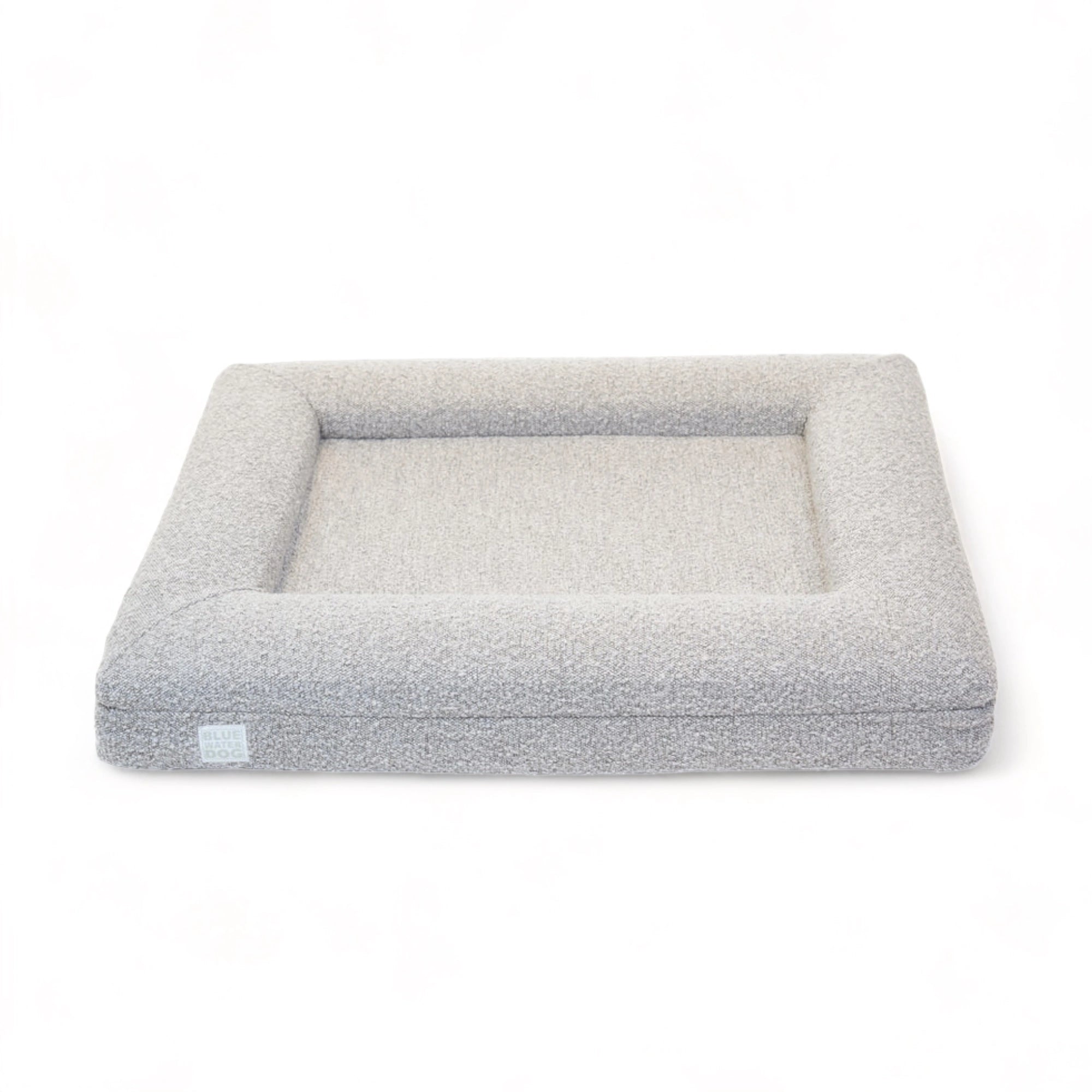 Front of a medium, sand-colored orthopedic memory foam rectangular boucle dog bed with bolsters.