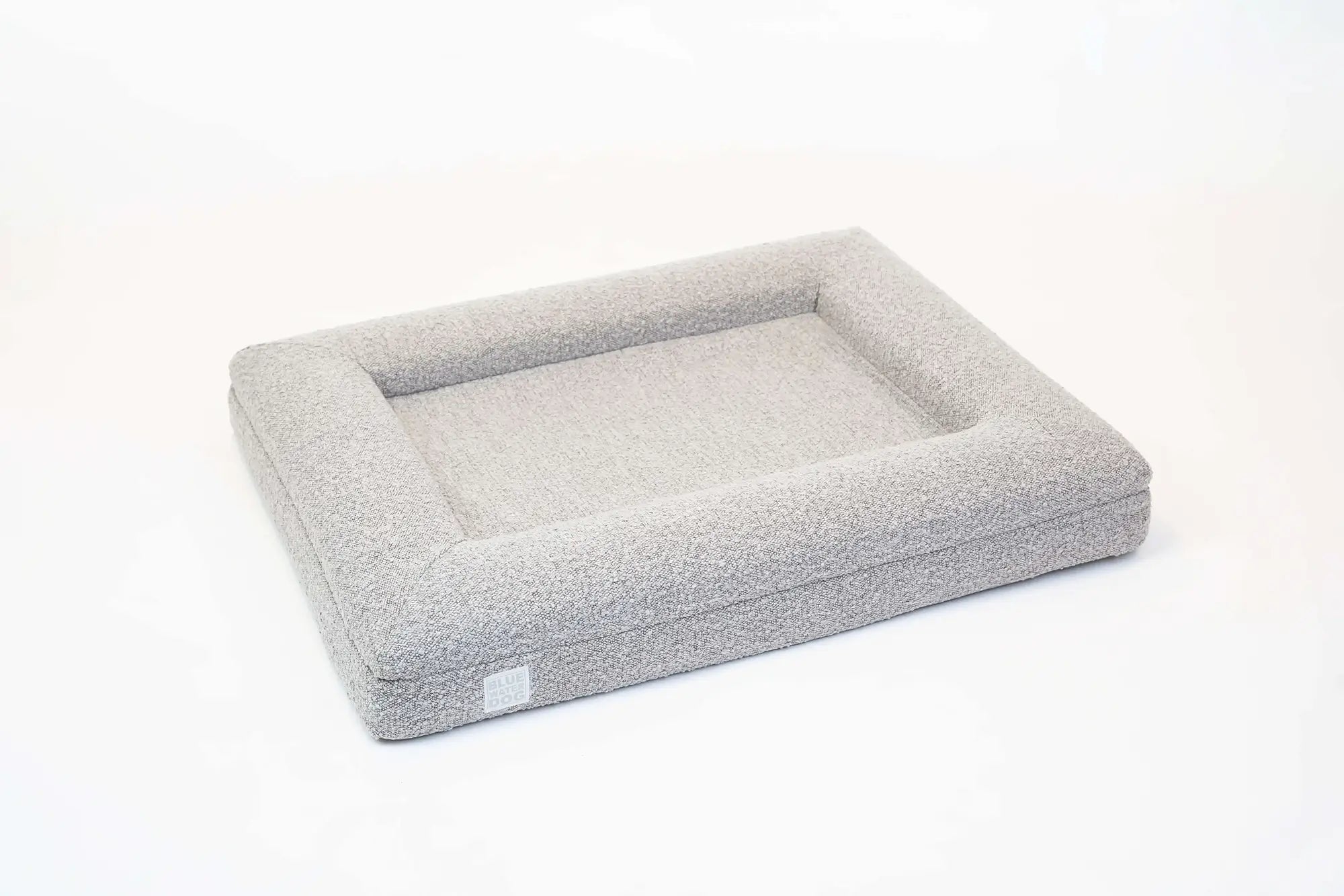 Side of a medium, sand-colored orthopedic memory foam boucle dog bed with bolsters.