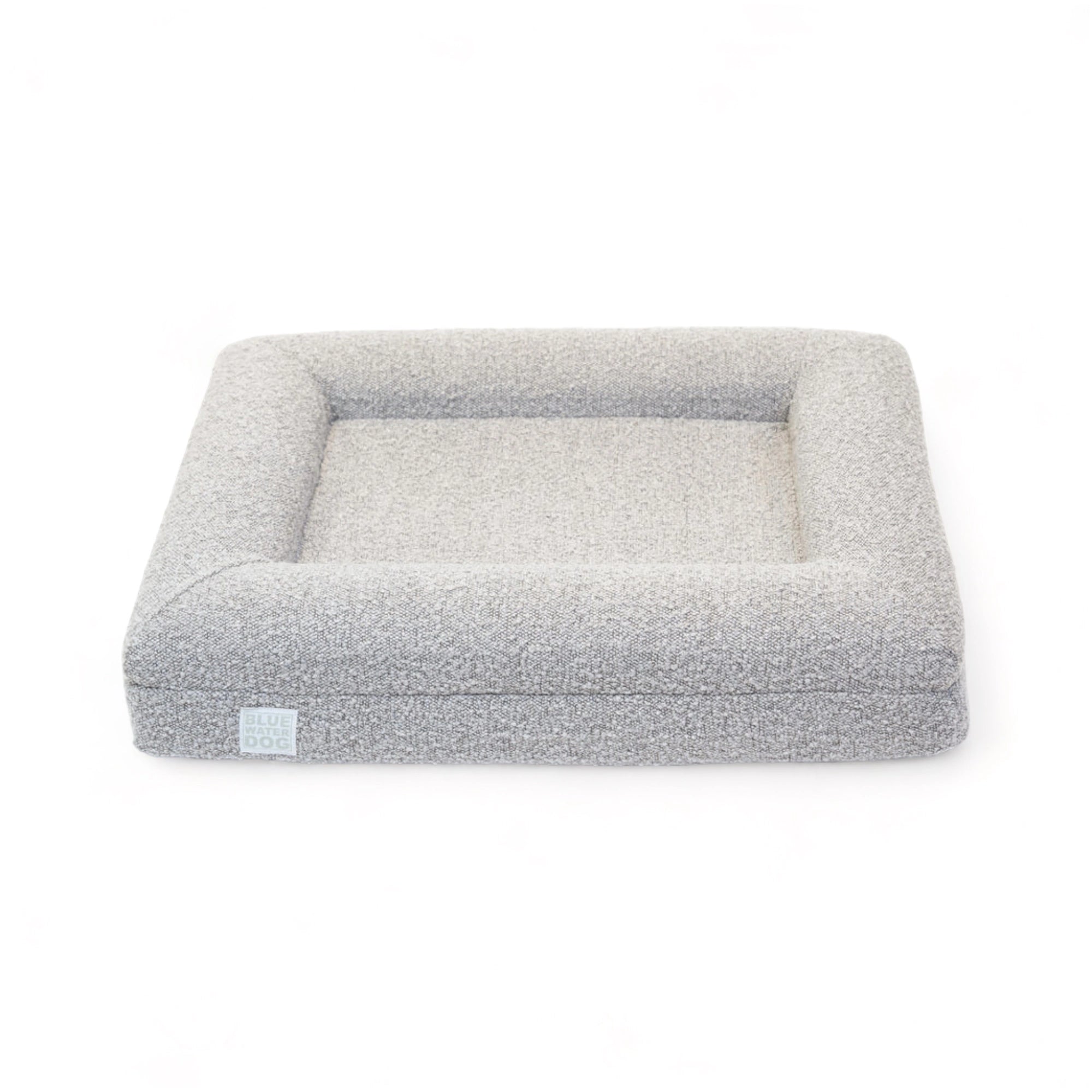 Front of a small, sand-colored orthopedic memory foam rectangular boucle dog bed with bolsters.
